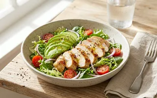 Ensalada de pollo y aguacate con hojas verdes y tomates cherry